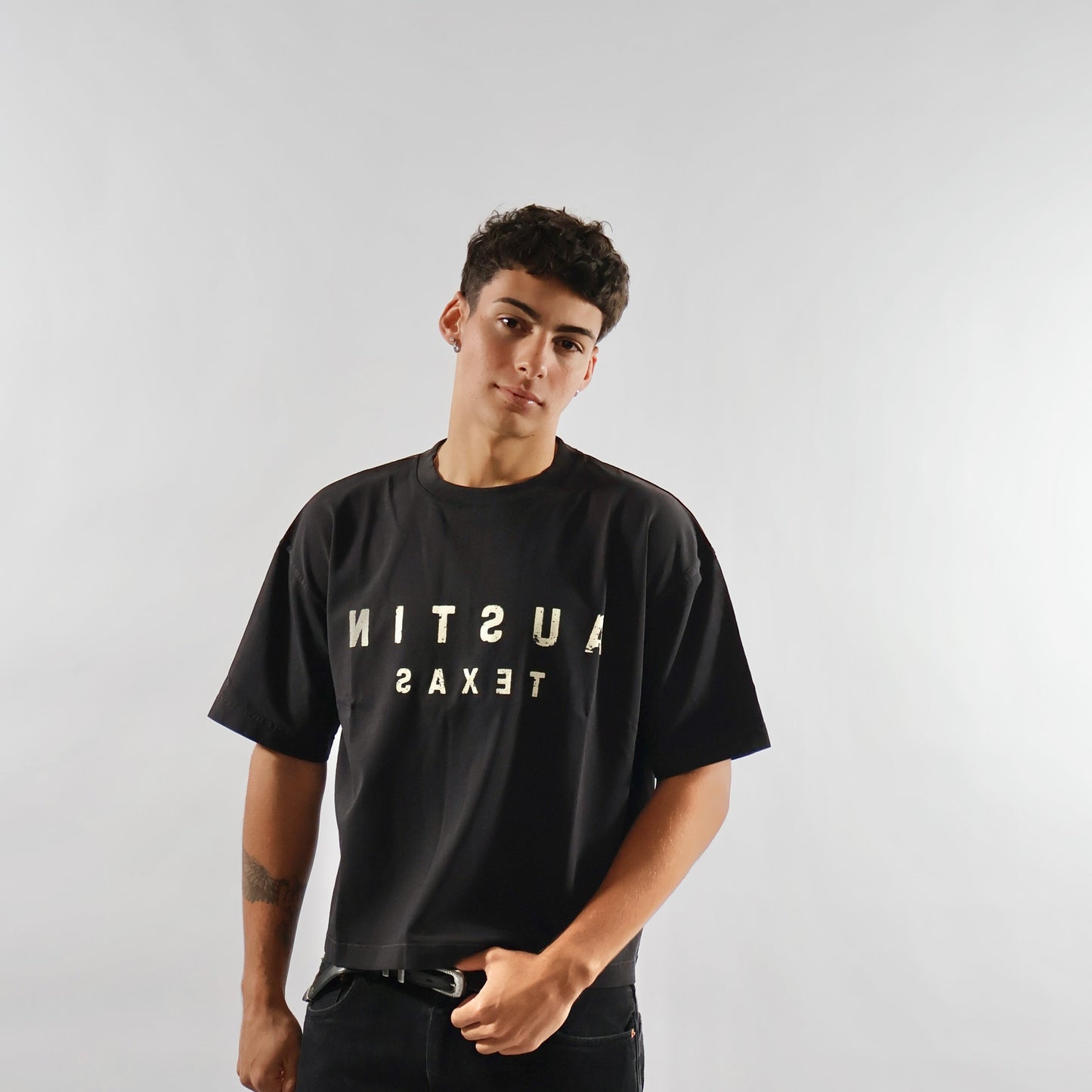 Person wearing a black t-shirt with 'Austin Texas' text on a plain background