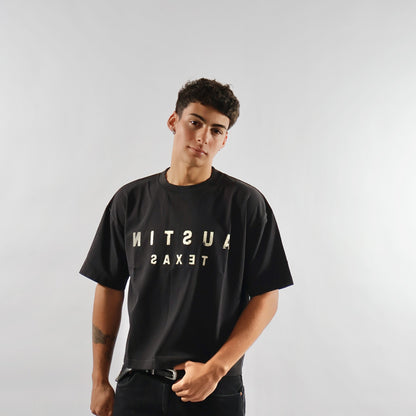 Person wearing a black t-shirt with 'Austin Texas' text on a plain background
